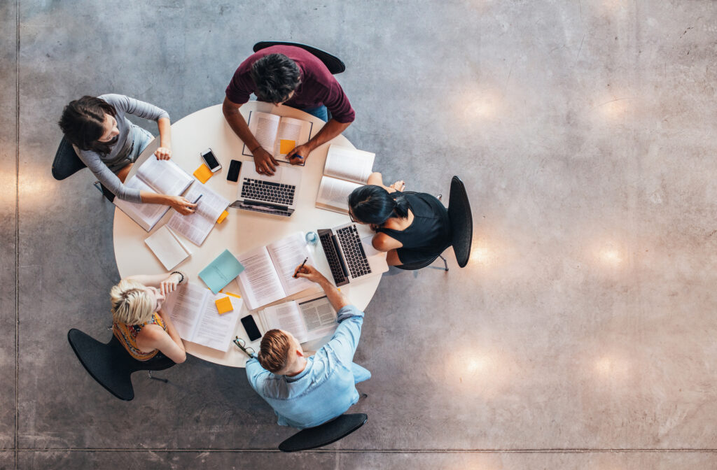 Top view of group of college students sitting together at table.